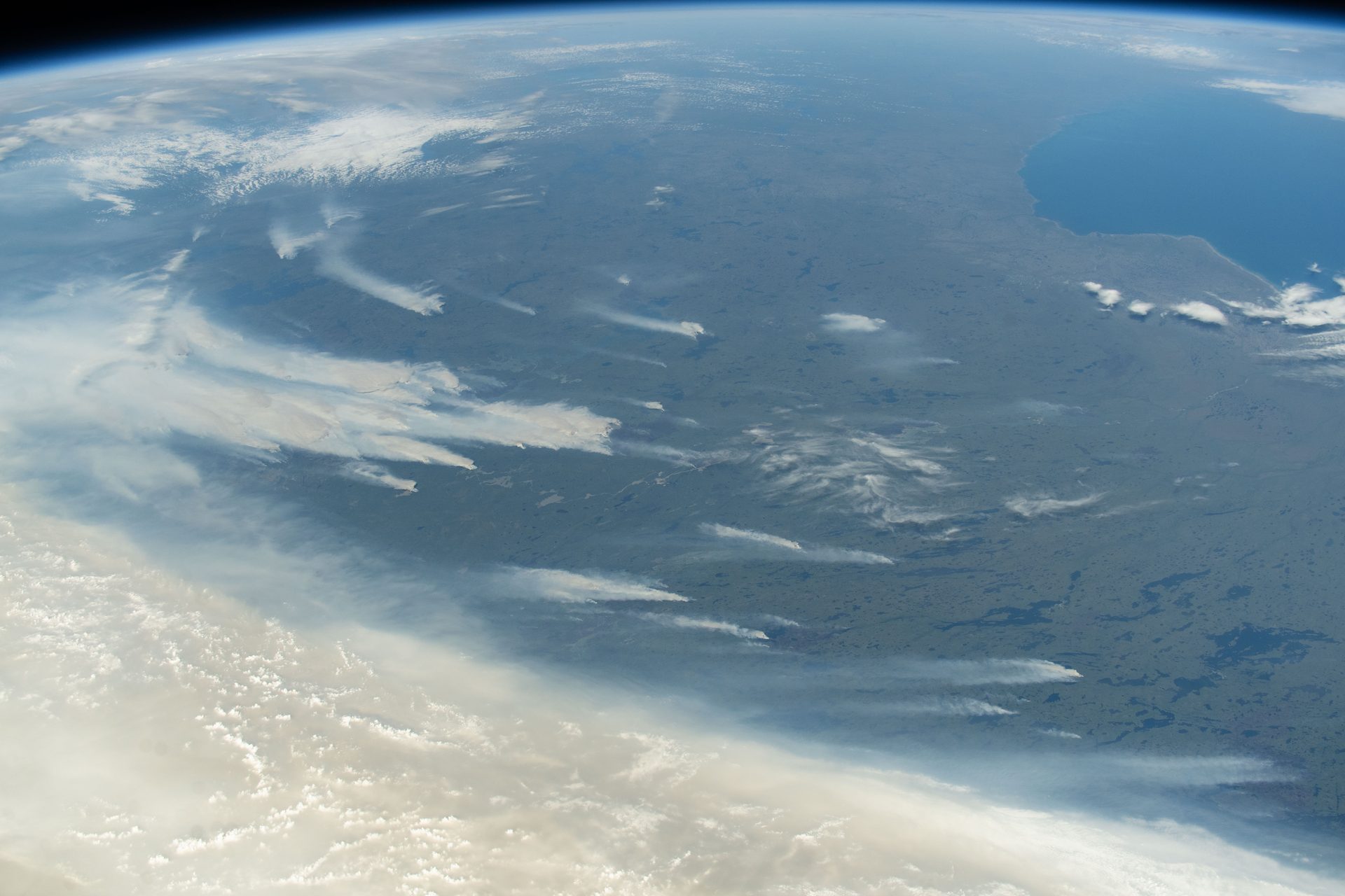 Wildfires burning across Canada's central provinces, with smoke drifting south, seen from the International Space Station